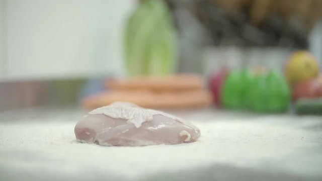 Fresh raw chicken breast dropped into flour. Slow Motion