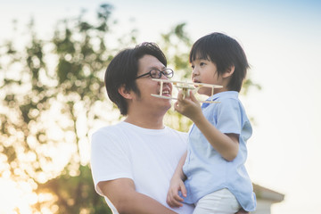 Obraz premium Asian father and son playing wooden airplane together