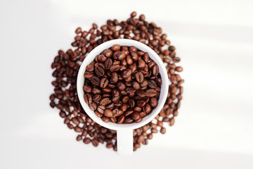 Top view of cup with heap of aromatic coffee beans in it isolated on white background
