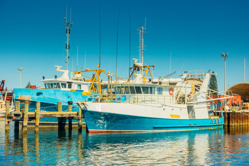 Naklejka premium Fishing Boats in a Harbour and a Blue Sky