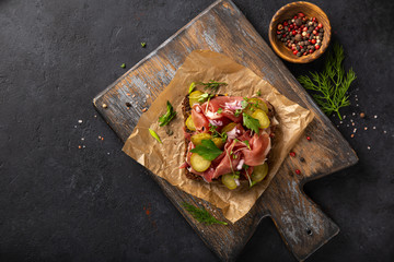 open sanwiche with dark rye bread, cured meat, pickled cucumber  and red onion
