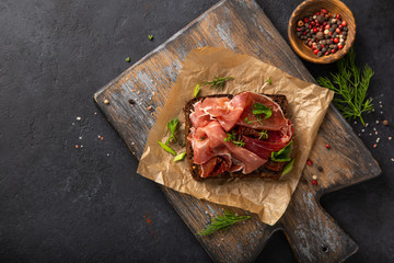 open sanwich with dark rye bread, prosciutto and sun dried tomatoes
