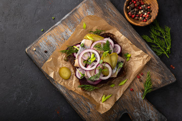open sanwich with dark rye bread, beetroot, marinated herring, pickled cucumber and red onion