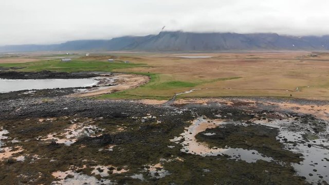 Aerial recording of Ytri Tunga beach in Iceland. Moving towards the land and showing mountains with clouds in the background.