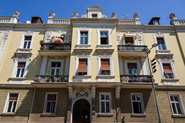 Fototapeta na wymiar Belgrade, Serbia - April 19, 2018. Living architecture building facade in old town central street close view with details. Apartment building with brown shutters in Belgrade's historical center.