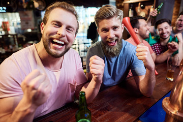 Young adult men friends cheering on soccer team