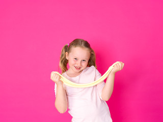 girl is playing with yellow slime in front of pink background
