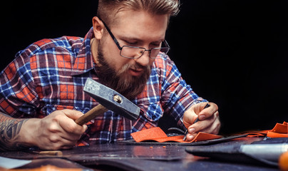 Artist working with leather creating leatherwork in the tanner shop