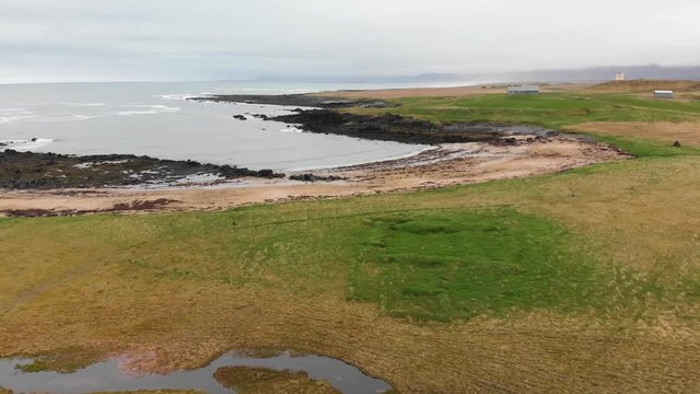 Aerial footage going over a field on Ytri Tunga beach located in Iceland. Moving towards the coastline.