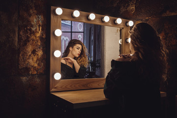 Beautiful fashion model woman posing near the mirror