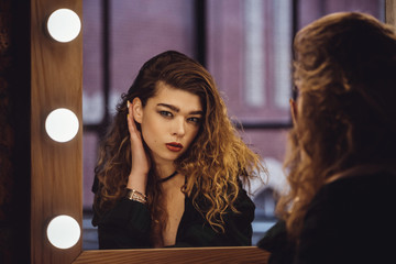 Beautiful fashion model woman posing near the mirror