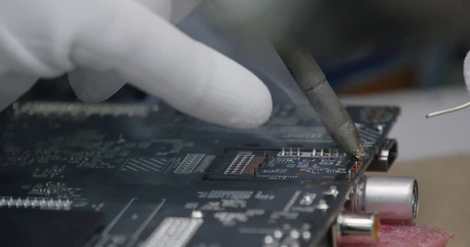 Modern production of TVs, view of the assembly line, the soldering process, electrician solders a microcircuit TV chips on the conveyor.