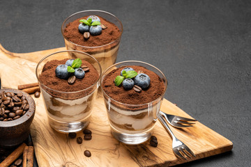 Classic tiramisu dessert in a glass with blueberries on dark concrete background