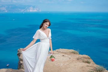 A beautiful bride standing on the coast. The bride in mountains. Wedding