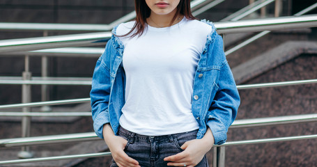 Girl wearing t-shirt and cotton jacket posing against street , urban clothing style