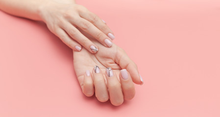 Beautiful young woman's hand with perfect manicure on pink background. Flat lay style.
