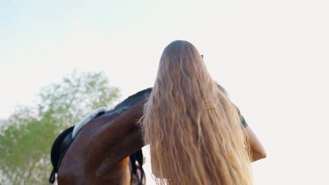 Long-haired girl strokes his horse. Beautiful girl with a horse by the river.