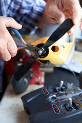 Close Up Of Senior Man Working On Model Radio Controlled Aieroplane In Shed At Home