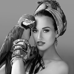 monochrome portrait of young attractive woman in african style with ara parrot on her hand on colorful background © k8most