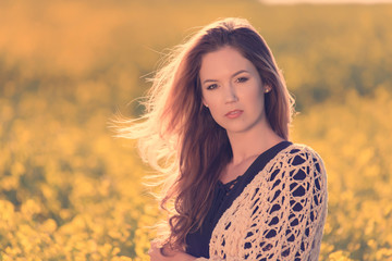 Fototapeta premium Portrait of beautiful woman in rapeseed field