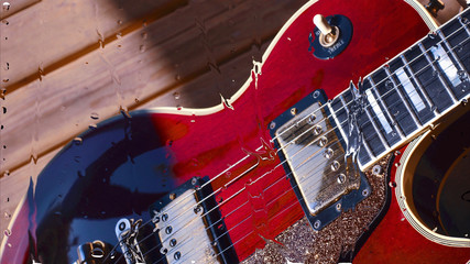 electric guitar behind the glass with water drops . closeup