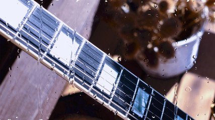 electric guitar behind the glass with water drops . closeup
