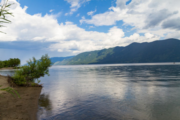 The shore of Lake Teletskoye in Altai mountains. Beautiful summer landscape. Rain drops on water.