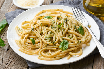 Pesto spaghetti pasta with basil, garlic, pine nuts, olive oil. Rustic table, side view
