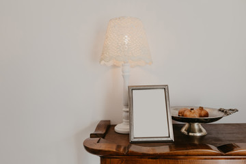 chest of drawers with a lamp candelabra and a vase against a white wall- Image