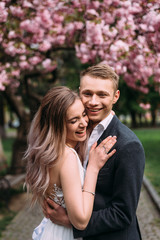 cute couple standing under a flowering tree hugging and smiling