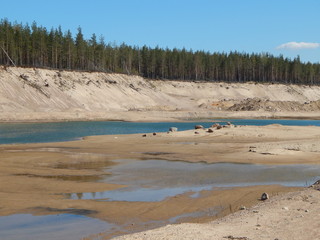 Abandoned sandpit with a pond and forest on the horizon, a beautiful summer landscape