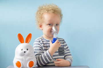 Sweet little boy having inhalation for easy cough at home. Allergy and health care concept. Copy space