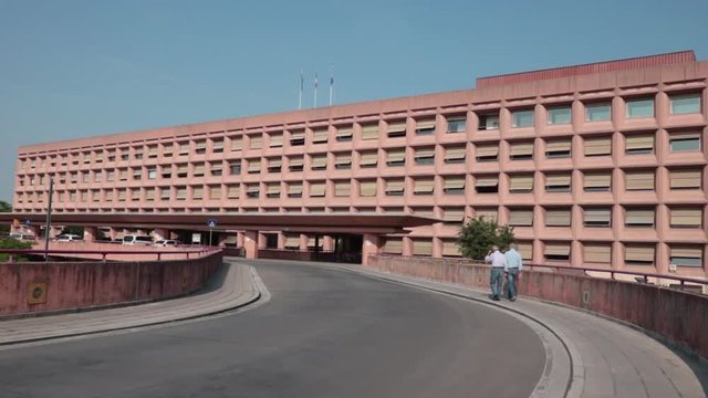 two seniors walking into the hospital, panning shot of outdoor health care structure in Udine (Italy)