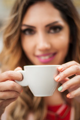 Portrait of woman sitting in outdoor cafe and drinking coffee