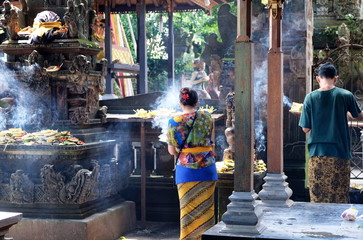 Bali, Indonesia - March 5, 2019: Illustrative Editorial showing traditional Balinese male and female in ceremonial clothing praying and giving offering in one of the temples of Ubud.