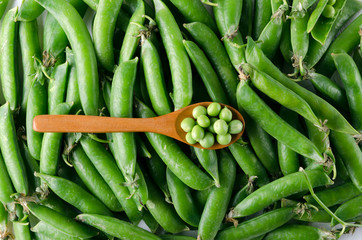 Fototapeta premium Top view of spoon of peas.Peas in pods as a background