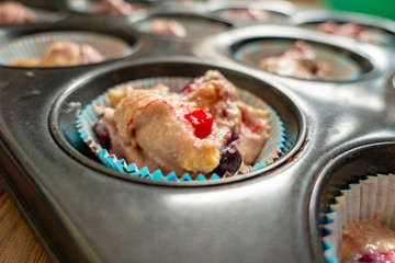 raw dough with fruits for delicious muffins in the tin