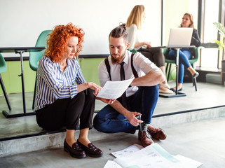 Two business people looking at paper documents in an office, talking.