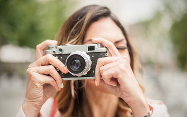 Woman photographing with vintage film camera on city street