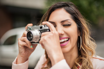 Woman photographing with vintage film camera on city street