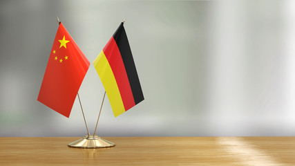 Chinese and German flag pair on a desk over defocused background  - 270180300