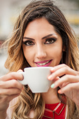 Portrait of woman sitting in outdoor cafe and drinking coffee