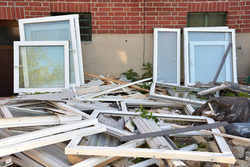 Many different construction debris from old plastic window frames of white color with glass.  The concept of replacing old window frames with new ones. The concept of protecting nature from plastic.