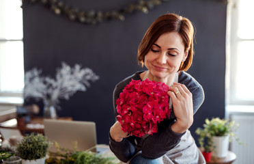 A portrait of young creative woman in a flower shop. A startup of florist business.