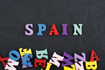 SPANISH word on black board background composed from colorful abc alphabet block wooden letters, copy space for ad text. Learning english concept.