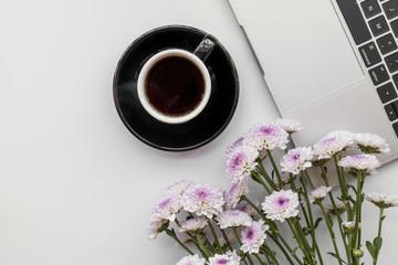 Flat lay with flowers and laptop with cup of coffee