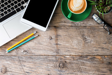 office supplies laptop, smartphone, notepad, tablet, pen and coffee cup on a wooden table background. View from above.