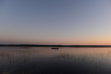 Fototapeta na wymiar Каyaking people on the calm water of the lake in the sunset light return from a hike