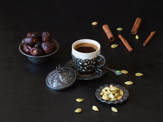 Obraz na płótnie Canvas Turkish coffee with dates and cardamom on the black table