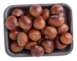 Fresh raw edible sweet chestnuts on black foam food tray isolated on white. Top view. Close-up.